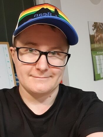 Photo of Elliott Spaeth, man with glasses and a rainbow baseball cap
